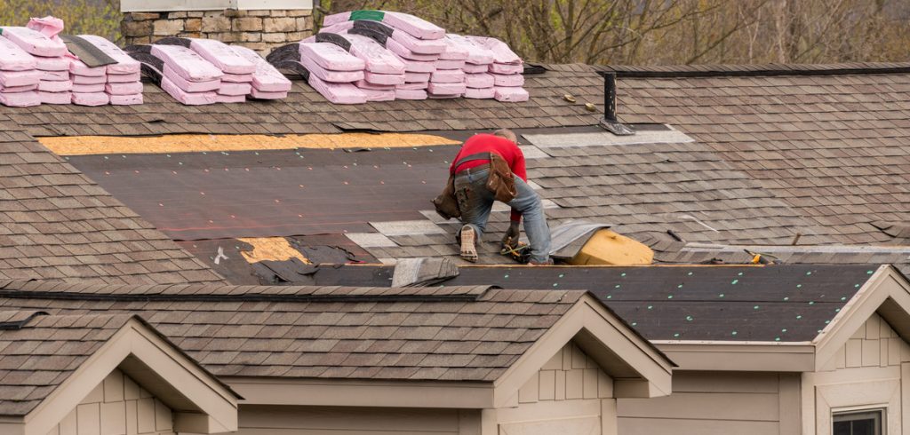 Roofing contractor removing the old shingles from a roof ready for reroofing