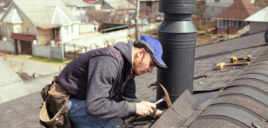 a professional master roofer with hammer repairs the roof.